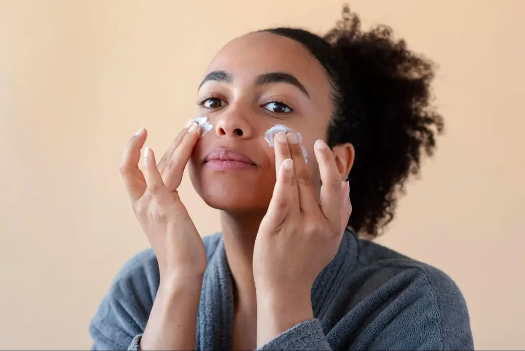 woman applying sunscreen after facial treatment from primeksin